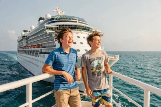 Deux adolescents riant au bord d'un grand navire de croisière avec l'océan en arrière-plan